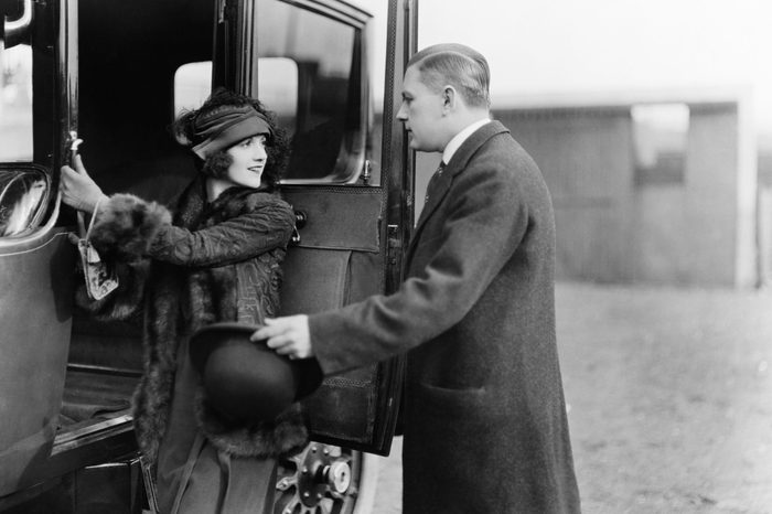 Profile of a man helping a young woman board a car