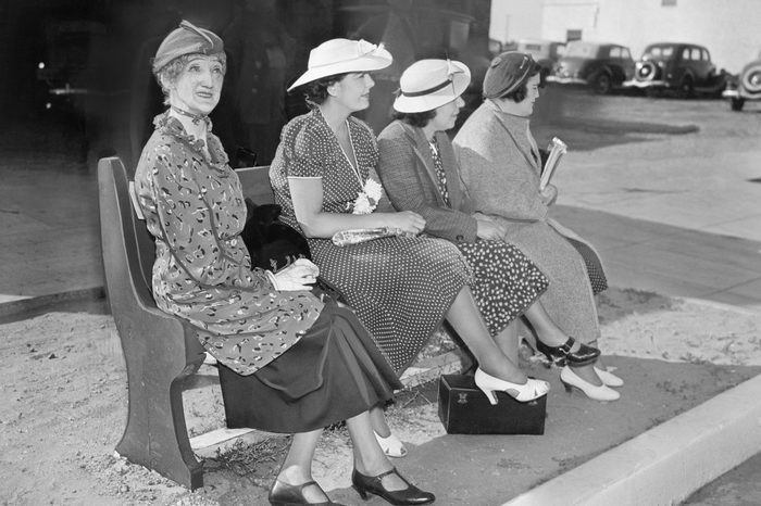 Four women sitting on a bench waiting for the bus