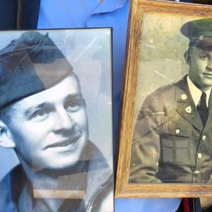 Two framed vintage photos show a man in military uniform, held by hands against a blue-shirt background.