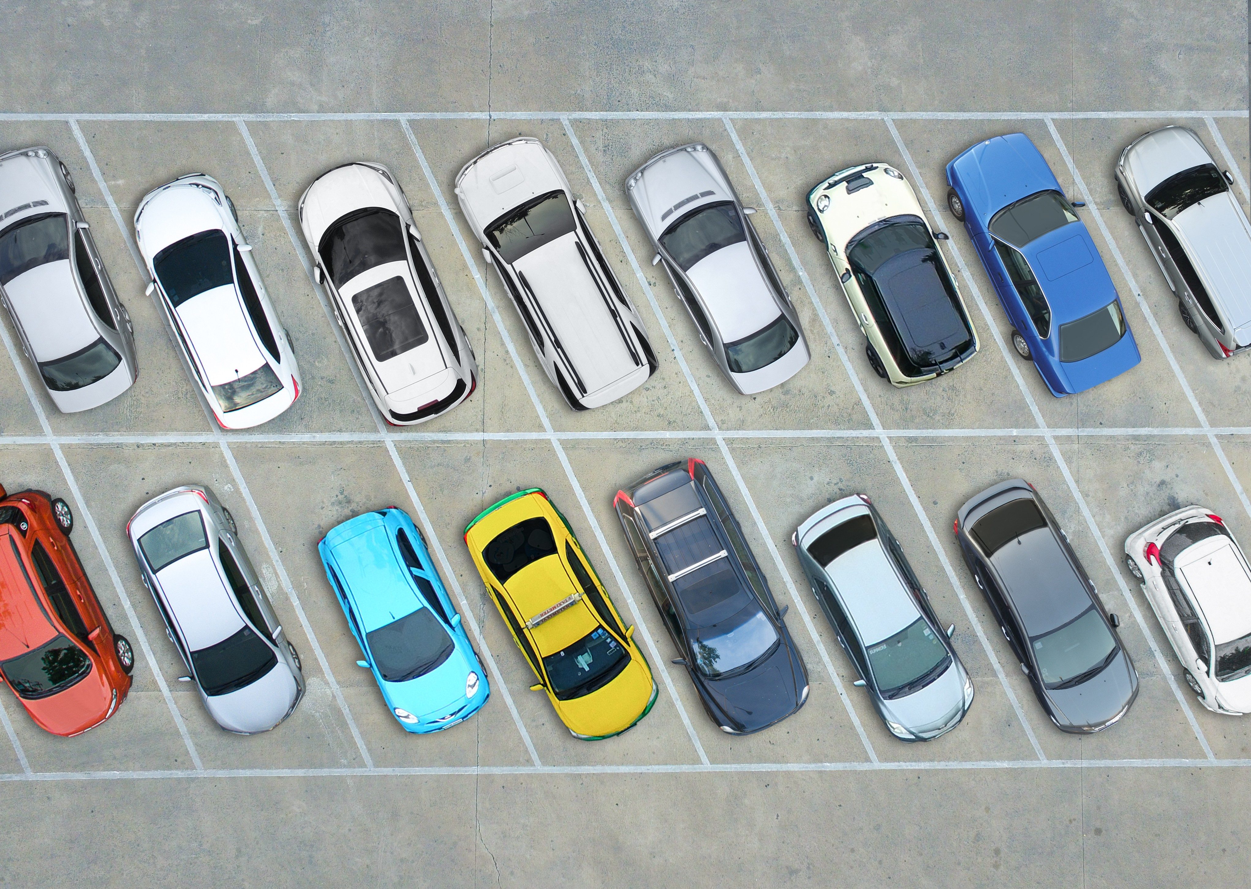 Cars parked neatly in a parking lot, viewed from above, featuring varied colors and sizes aligned within painted white lines on asphalt.