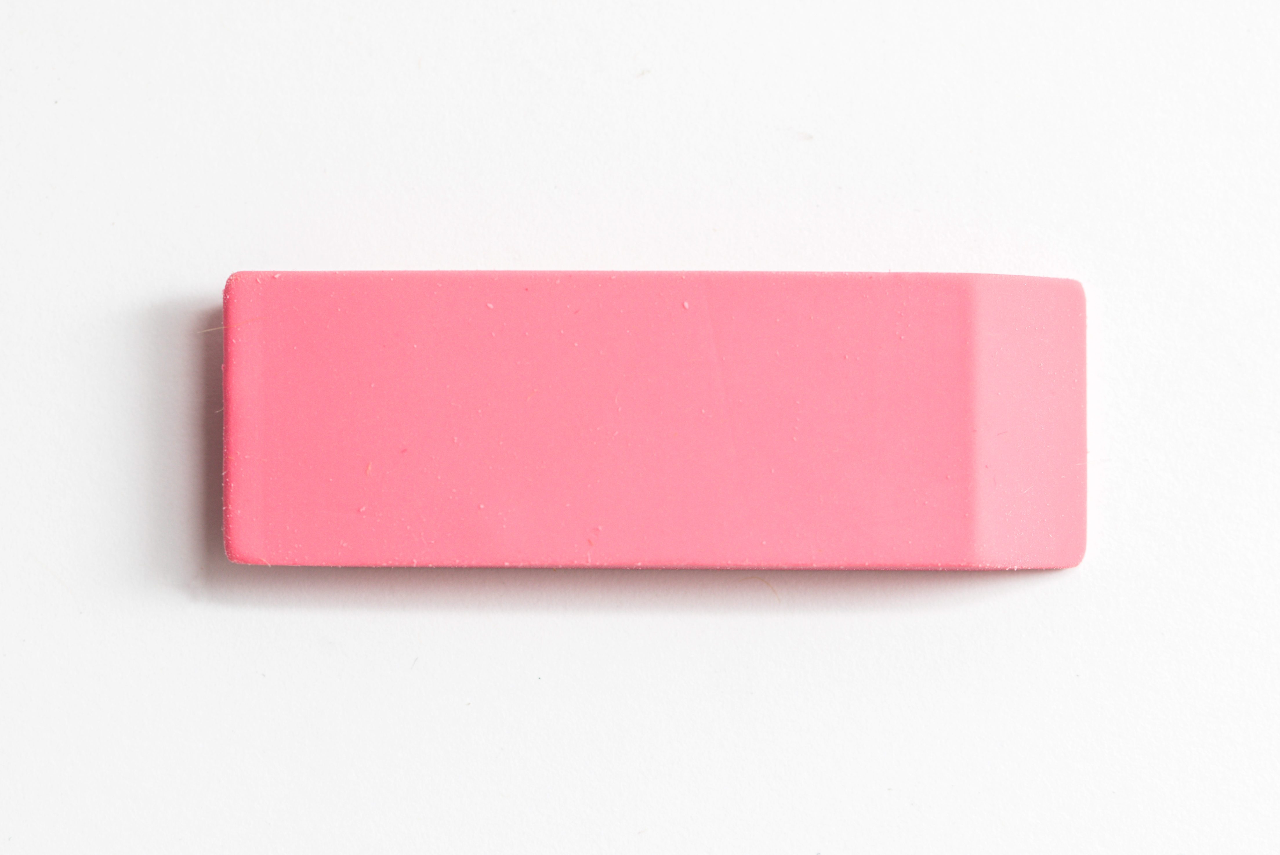 A pink rectangular eraser rests on a plain white surface.
