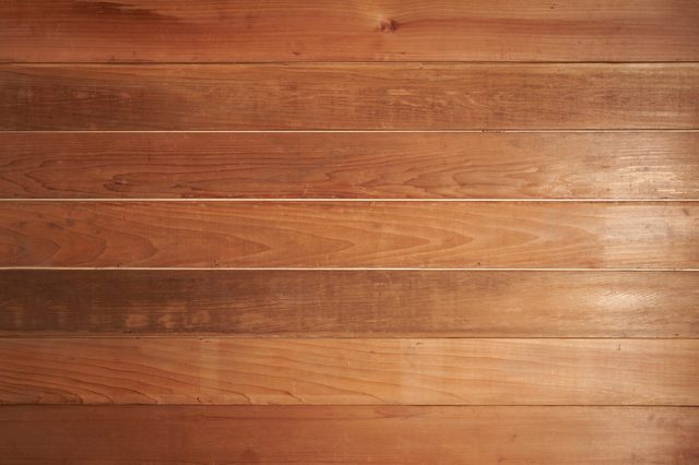 Wooden planks horizontally aligned, showing rich grain patterns, in a rustic indoor setting.