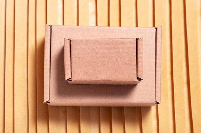 Two brown paper-wrapped packages placed on a surface with parallel vertical lines, contrasting with the neatly aligned background pattern.