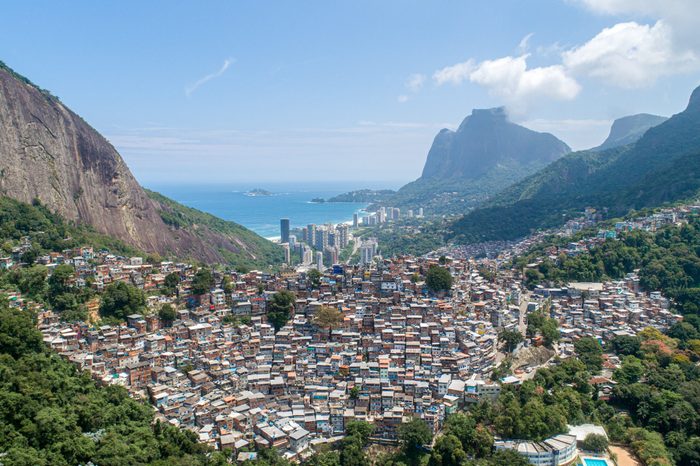 Aerial view of Favela da Rocinha, Biggest Slum in Brazil on the Mountain in Rio de Janeiro, and Skyline of the City behind