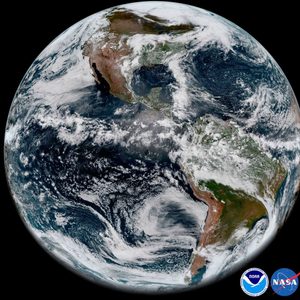 Earth appears vibrant, rotating amidst space; clouds swirl above continents, surrounded by dark void. NASA and NOAA logos are visible in the corner.