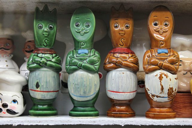 Ceramic figurines display, depicting chefs with letters "S" and "P" for salt and pepper, on a shelf with additional chef-themed decorations.