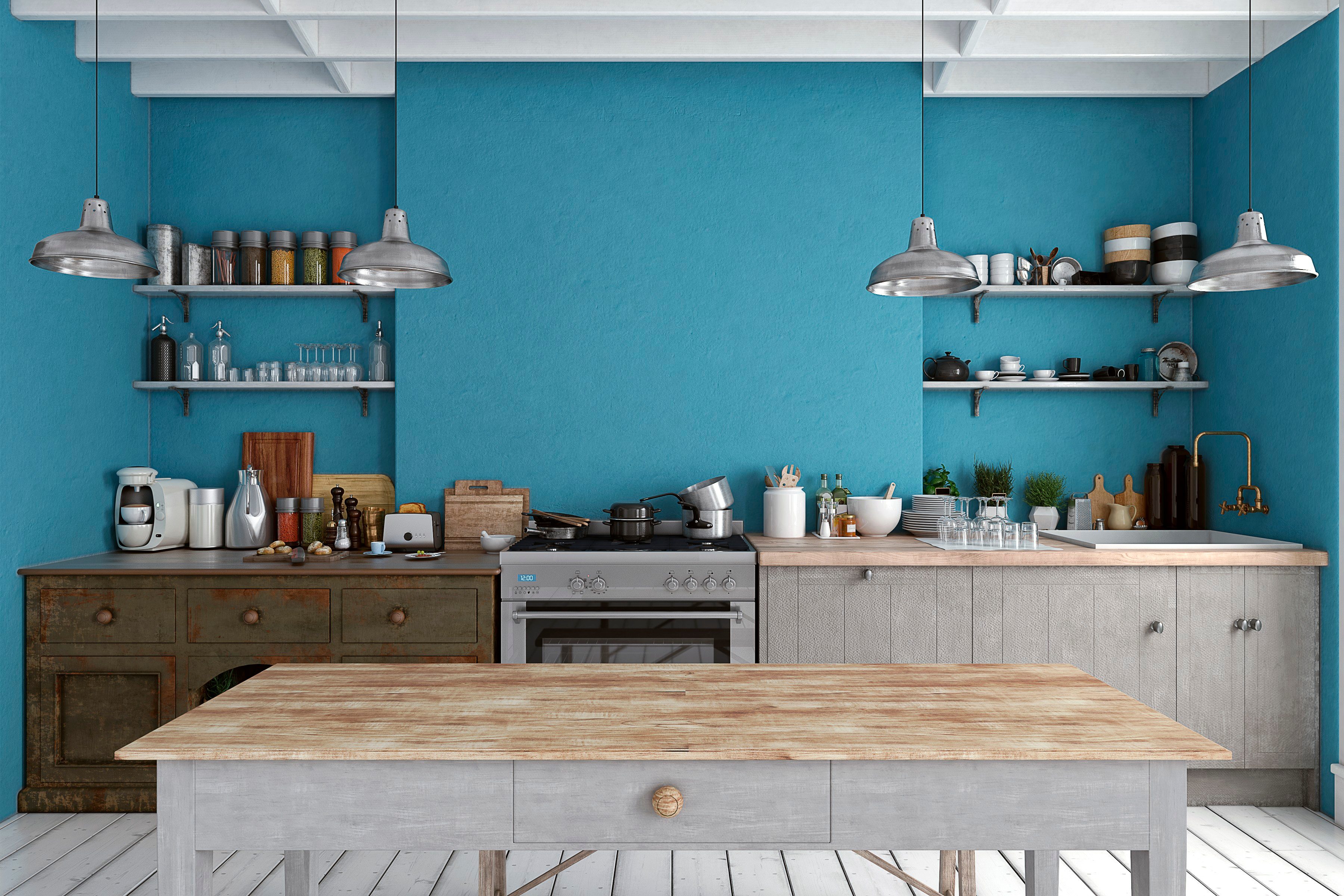 Rustic kitchen with wooden counters holds dishes and cookware; blue walls and metal shelves create a cozy atmosphere under industrial lighting.
