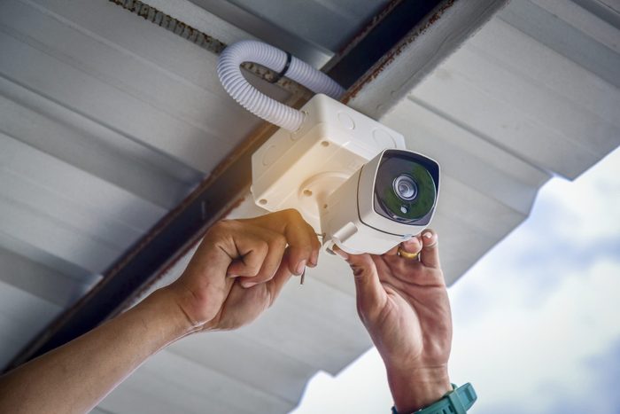 Technician installing CCTV camera by screwed for home security system and car park installed white plastic boxes for safe from water and rain
