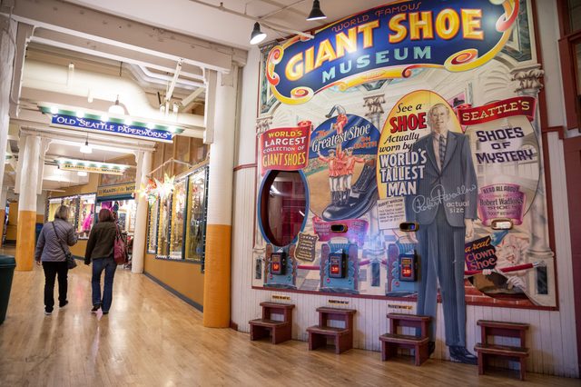 Giant shoe display features Robert Wadlow's shoe exhibits, with vintage signs and benches; two people walk down a colorful corridor.