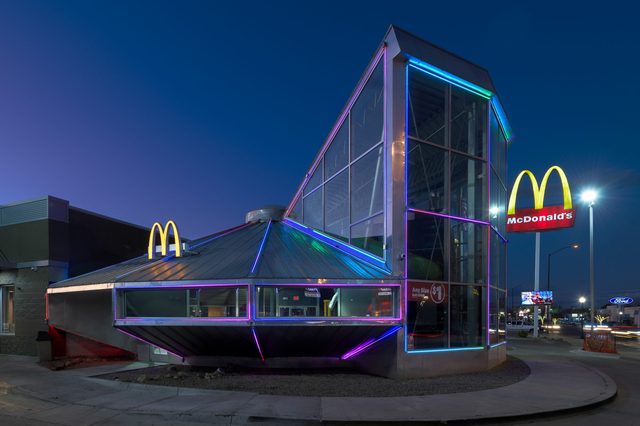 UFO-shaped building lit with neon lights, sitting beside a McDonald's sign; set in an urban night scene with surrounding businesses.