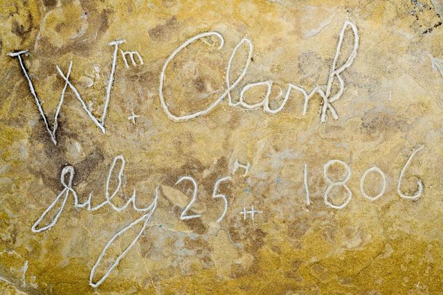 Stone surface shows carved text "Wm Clark July 25th 1806," etched into the rock, creating a historical inscription.