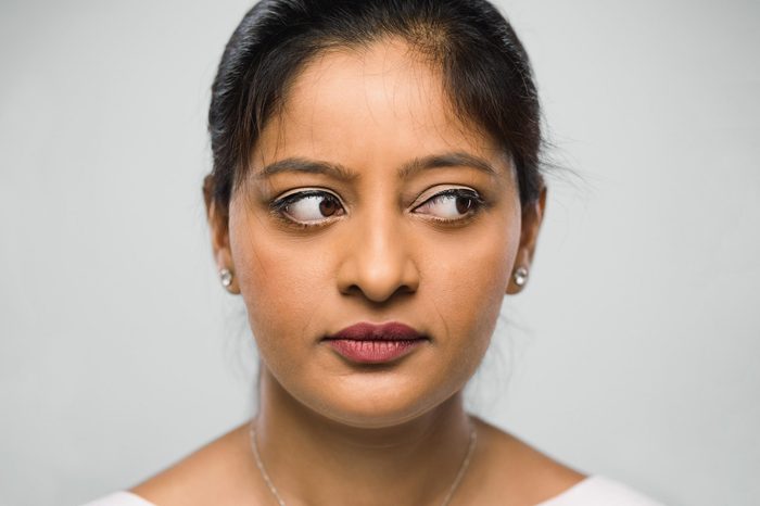 close up of woman's face and eyes. looking to the side. gray background.