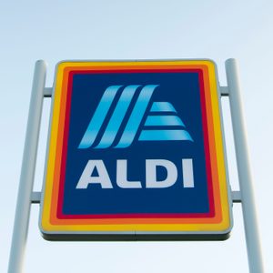 Aldi sign stands prominently against a clear sky, featuring blue, yellow, and red colors.