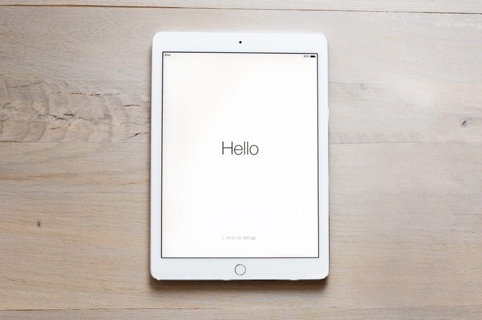 iPad Air 2 on wood table. says, "Hello" on the screen.