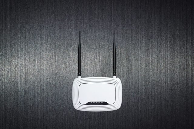 Router with antennas mounted on textured dark wall, idle.