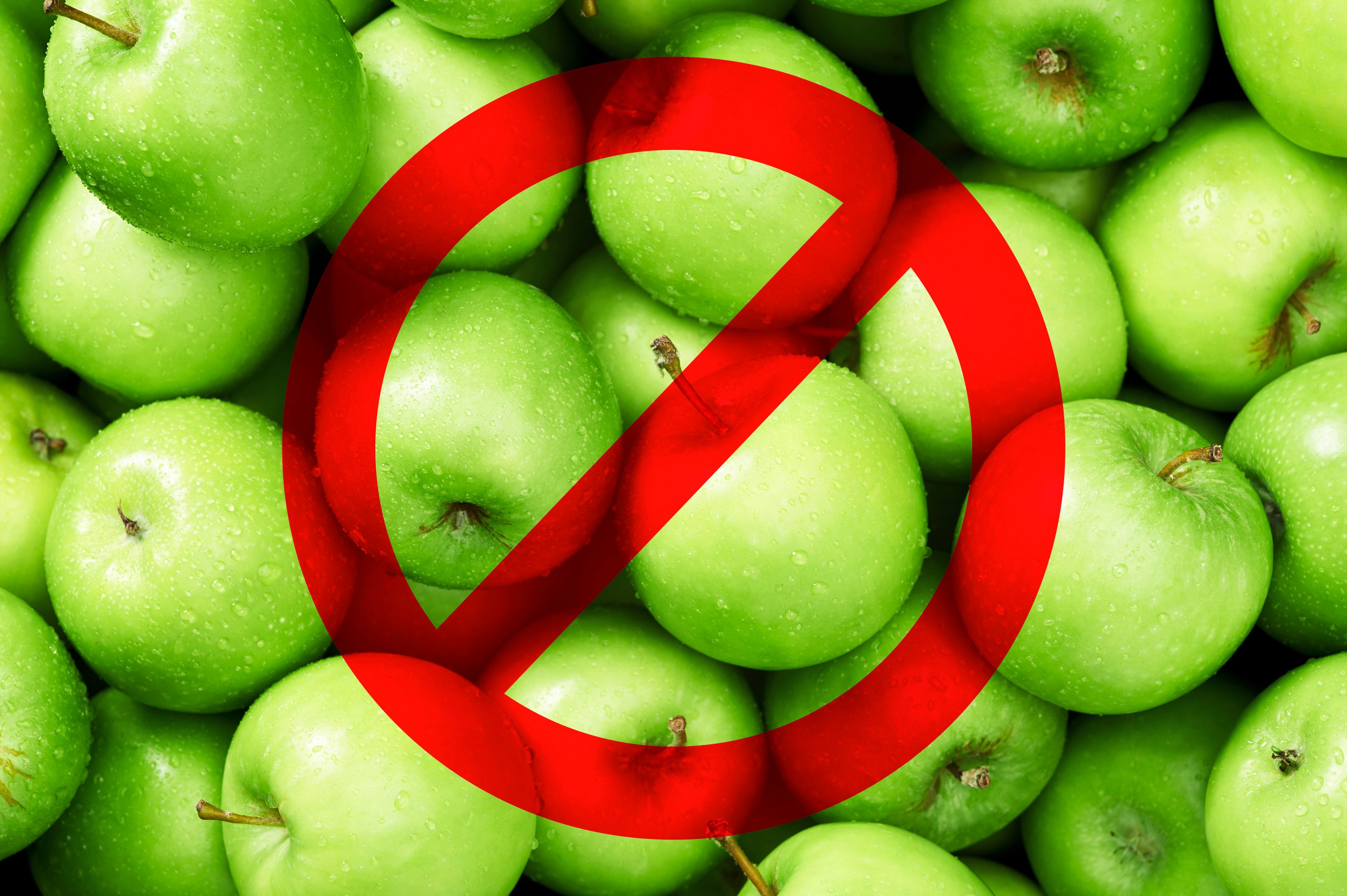 Green apples grouped together with a red prohibition symbol overlay, suggesting a ban or restriction on the apples.