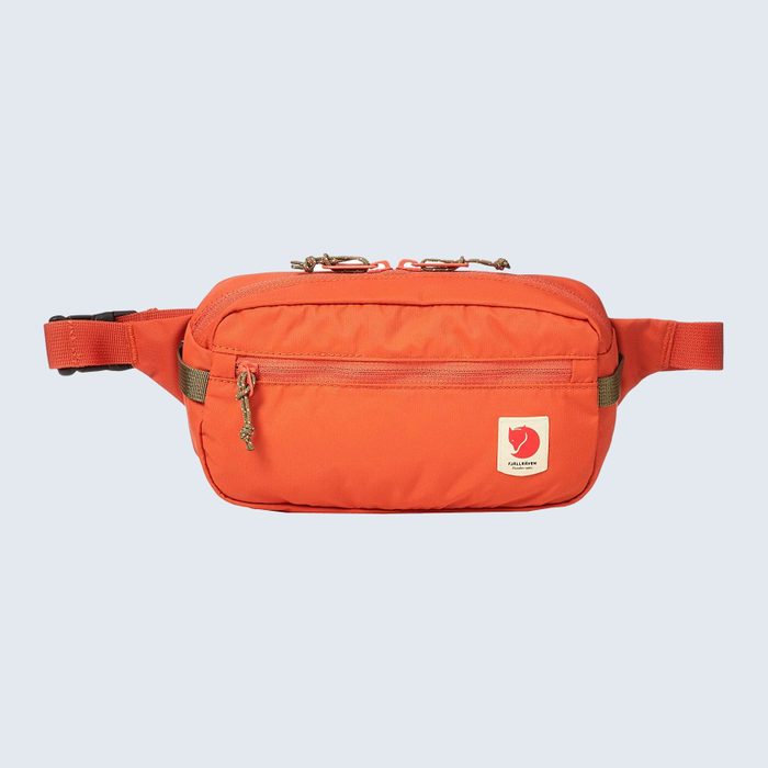 Orange waist bag sits on a light background, featuring a front zipper pocket and a small logo patch depicting a fox.