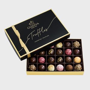 Box of assorted truffles displayed with lid tilted, featuring various designs, black packaging with gold accents, labeled 