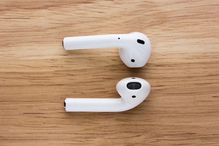 The airpods headset lies on a wooden table.