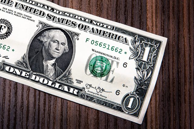 A one-dollar bill sits on a wooden surface, displaying George Washingtonâ€™s portrait and green treasury seal.