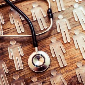 A stethoscope rests on wooden surface among transparent human figures, suggesting a theme of healthcare or medical analysis.