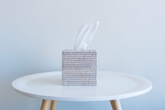 Tissue box on small white table against wall