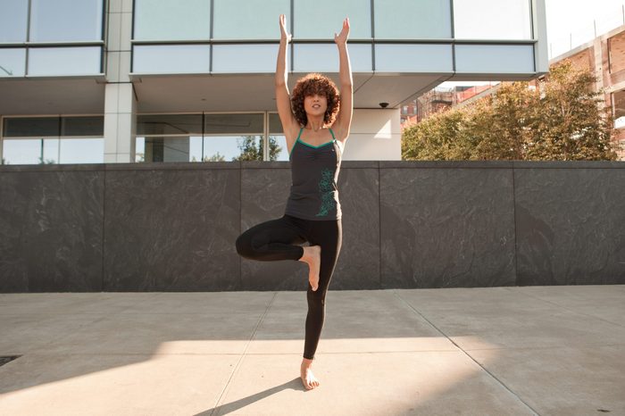 Young woman doing a tree pose on the pavement