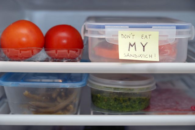 Container sits in refrigerator with handwritten note: "DON'T EAT MY SANDWICH!" Nearby are tomatoes and other containers.