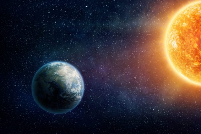 Planet Earth orbits in space, illuminated by the Sun. Stars fill the surrounding dark, cosmic background.