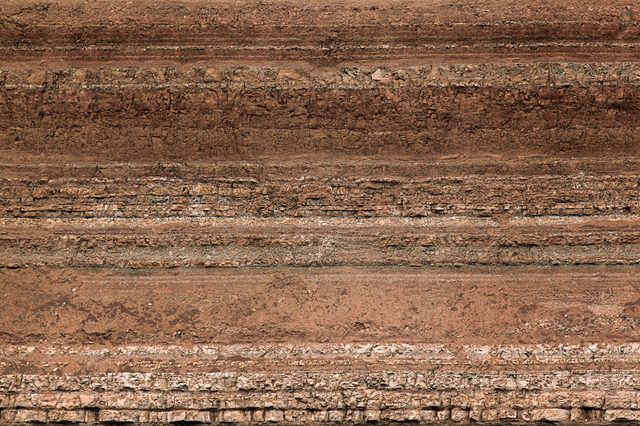 Earth layers form horizontal, parallel bands, showcasing strata with varying textures and colors, suggesting geological history and sedimentary processes.