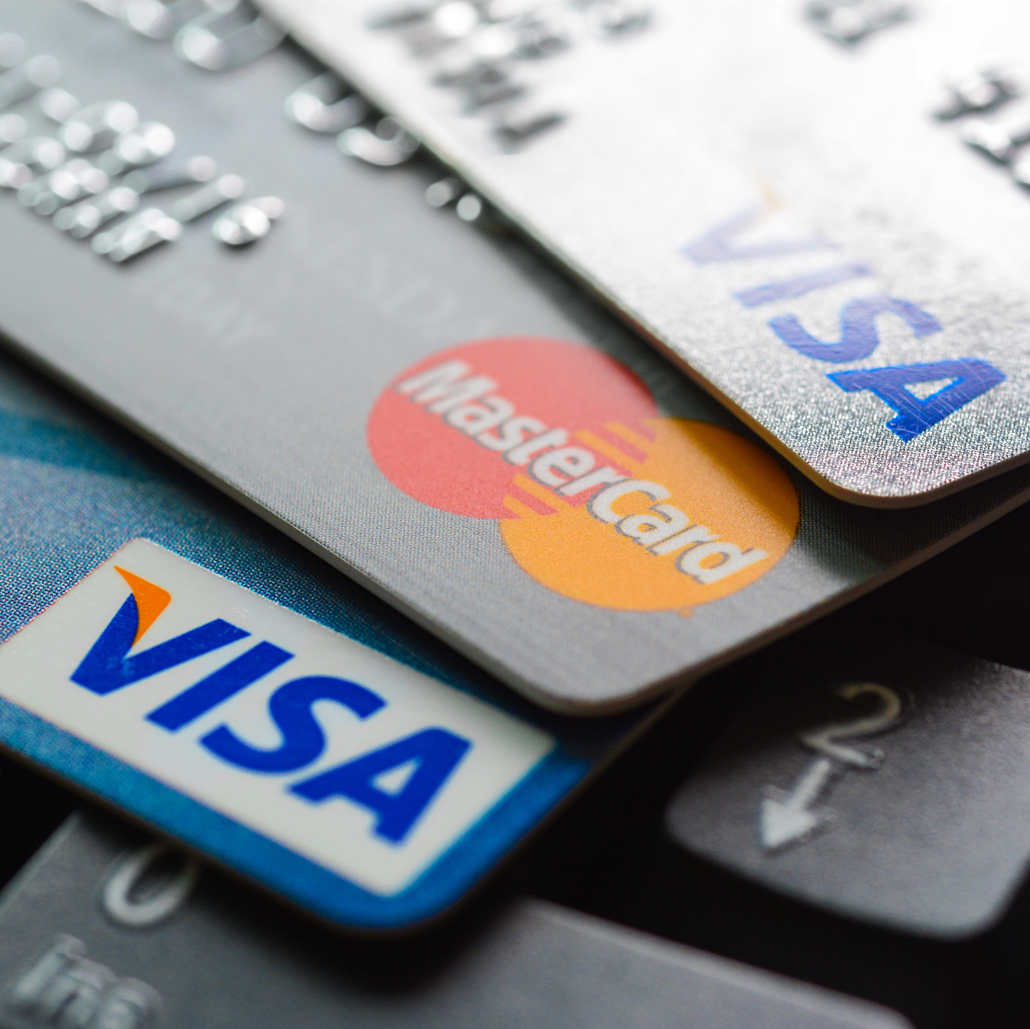 Credit cards stacked with Visa and Mastercard logos, resting on a keyboard, suggesting online transactions or banking.