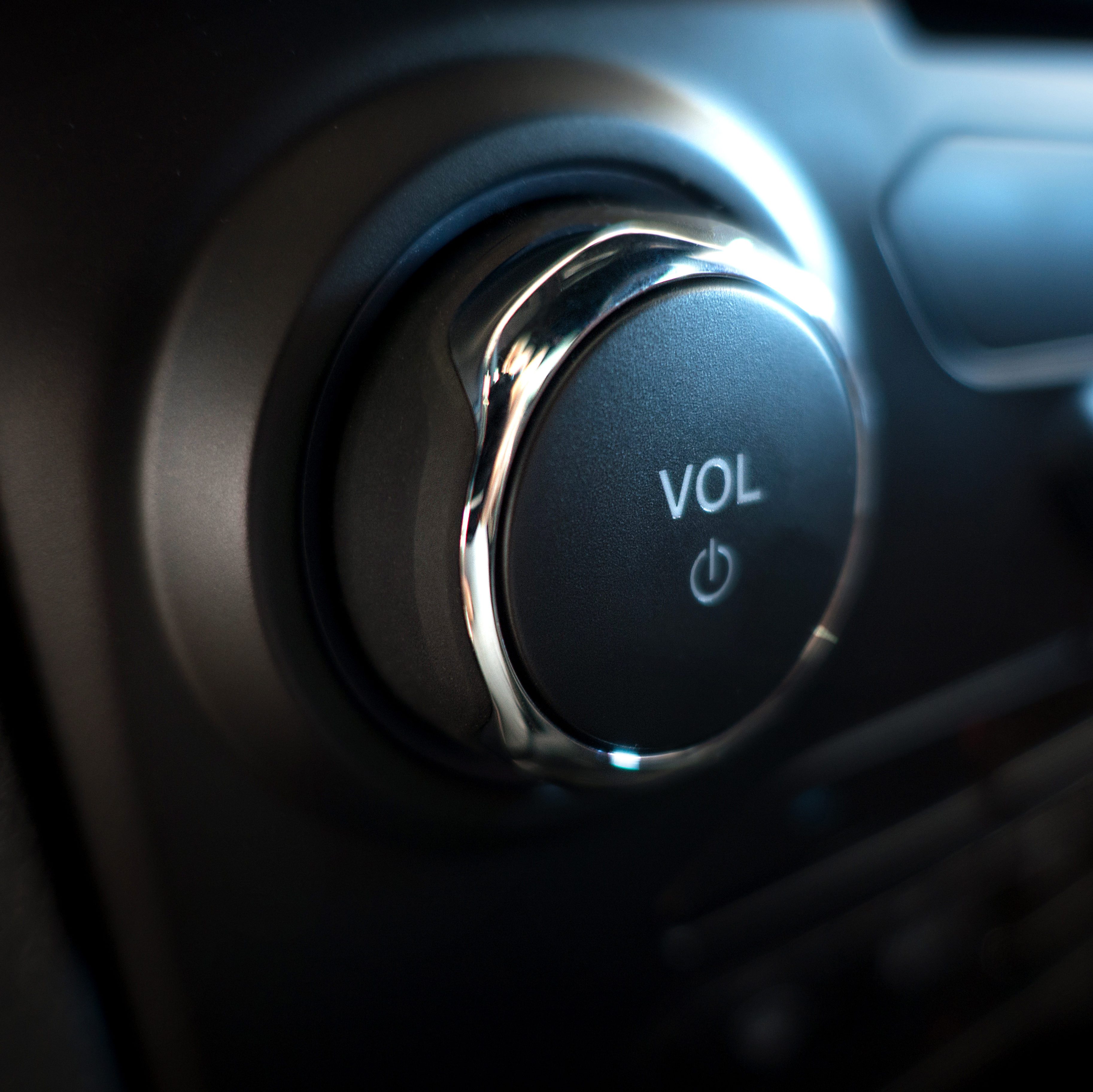 Volume knob shows "VOL," with power symbol, located on a sleek, dark dashboard panel.