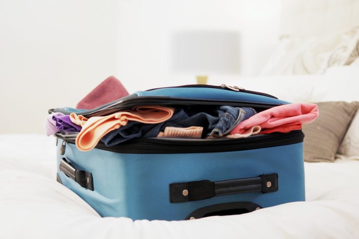 Overstuffed suitcase on top of bed.