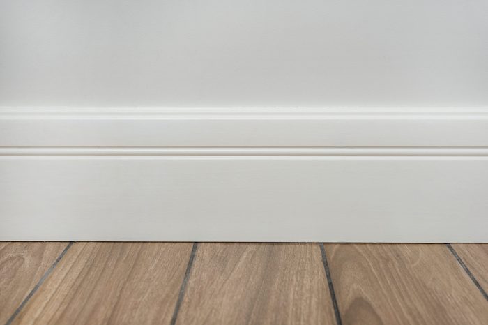 Light matte wall, white baseboard and tiles immitating hardwood flooring
