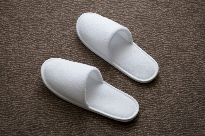White slippers resting on a textured brown carpet surface.