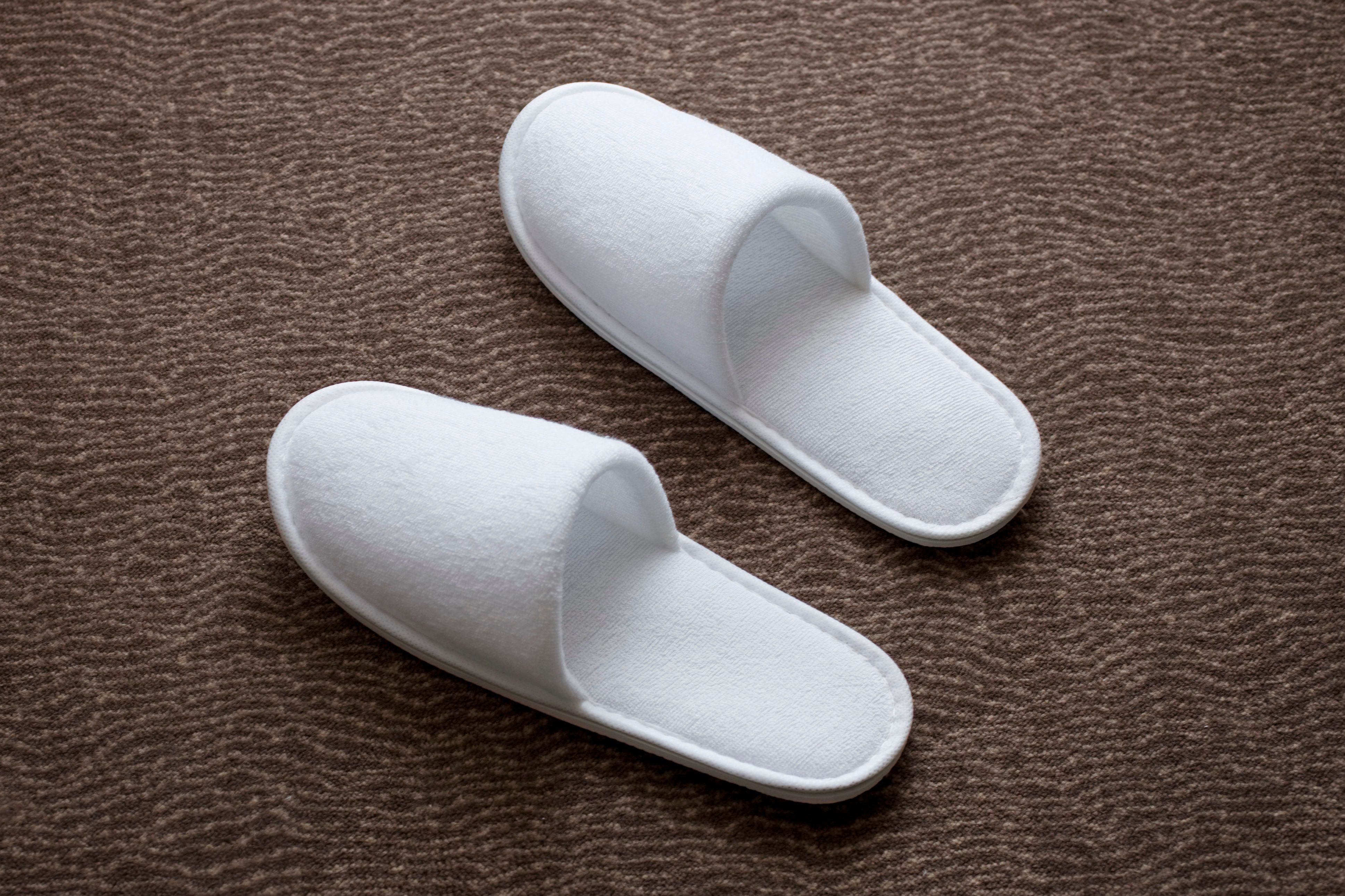 White slippers resting on a textured brown carpet surface.