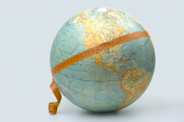 Globe wrapped with a measuring tape displaying numbers, set against a plain background.