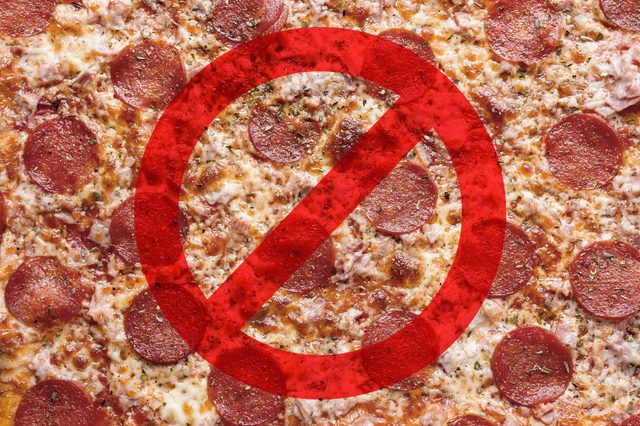 Pizza topped with pepperoni is shown with a red prohibition symbol overlay, indicating a restriction.