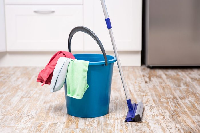 Plastic bucket with cleaning supplies in home