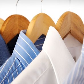 Shirts hanging on wooden hangers; blue and white colors; close-up view.