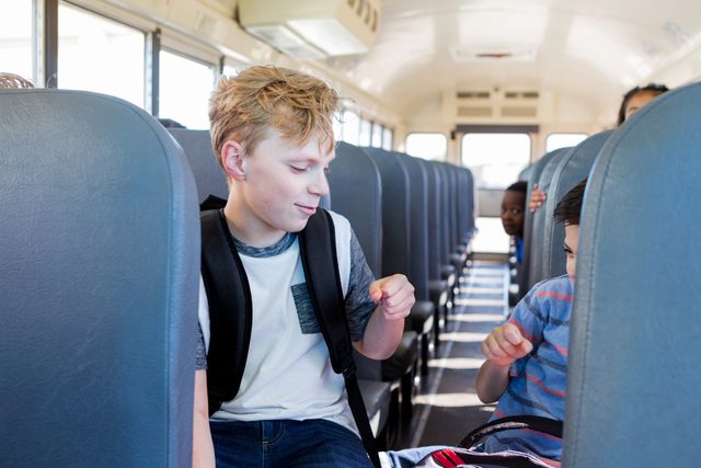 Friends fist bump on school bus