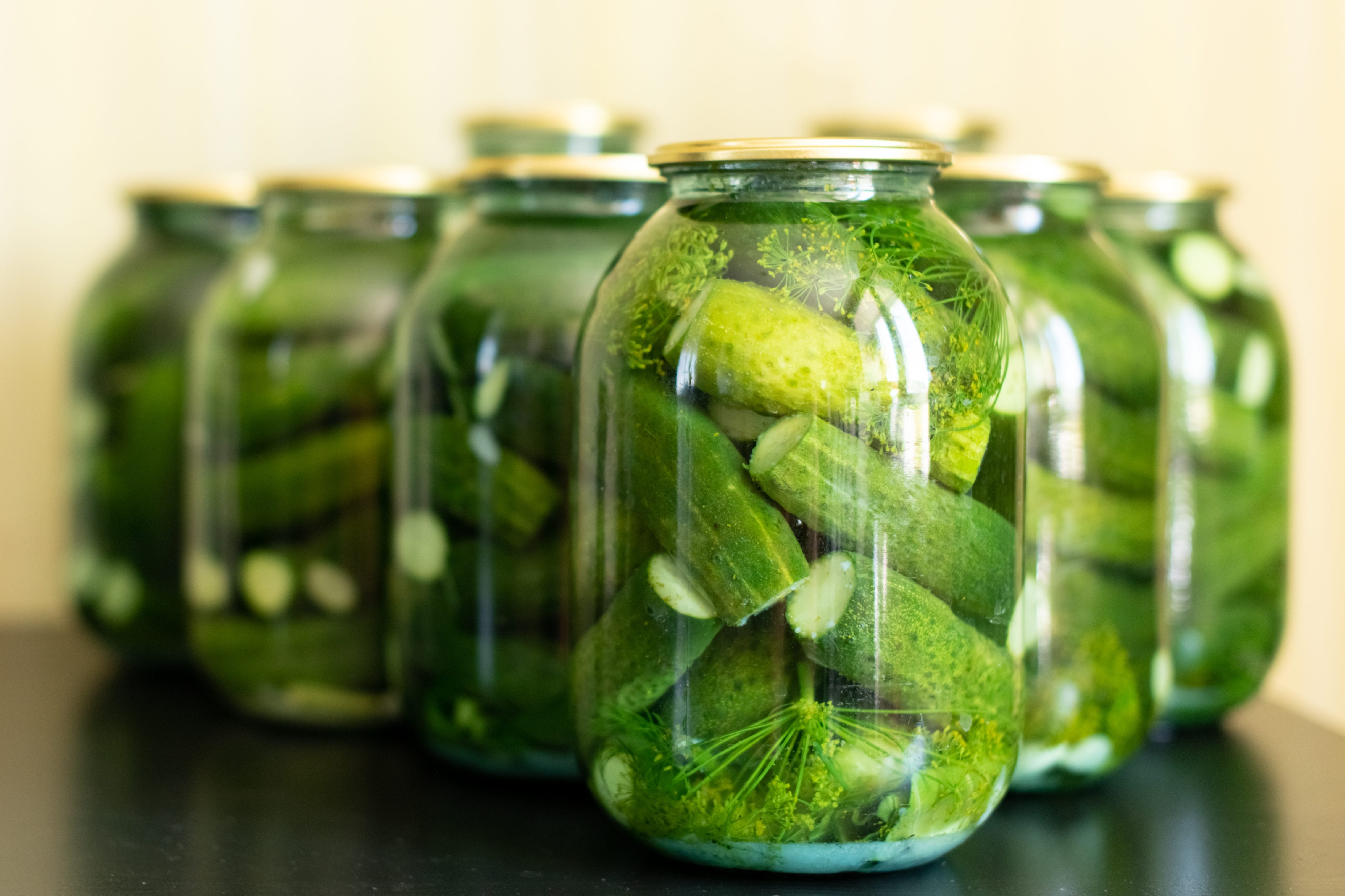Pickled cucumbers in glass jar on a gray wooden table.