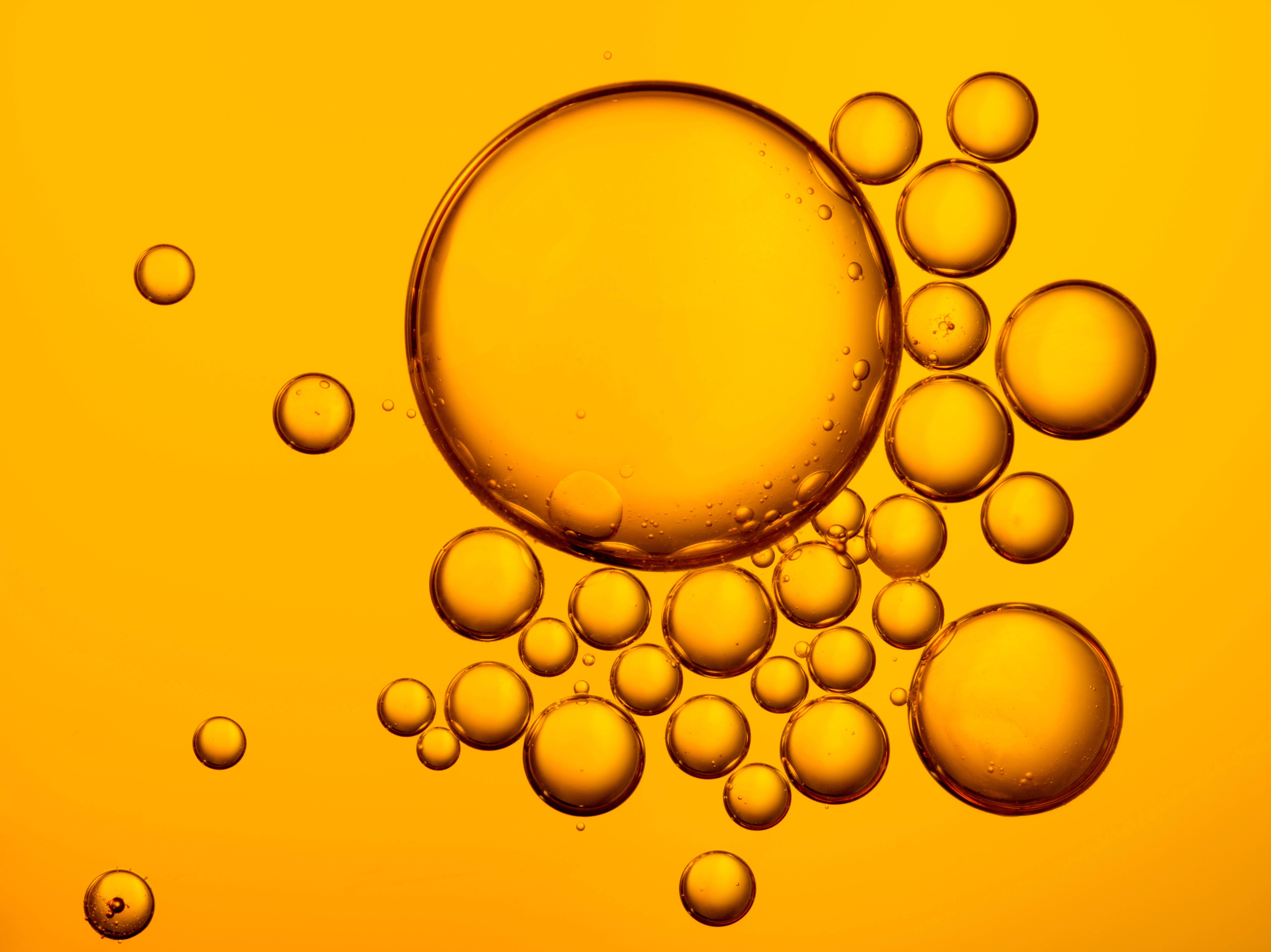 Bubbles cluster together, floating against a vibrant orange background, creating a lively and abstract visual.