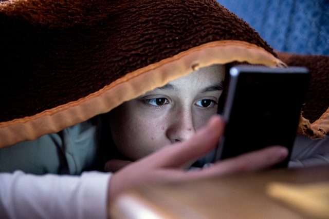 girl in bed texting on smartphone