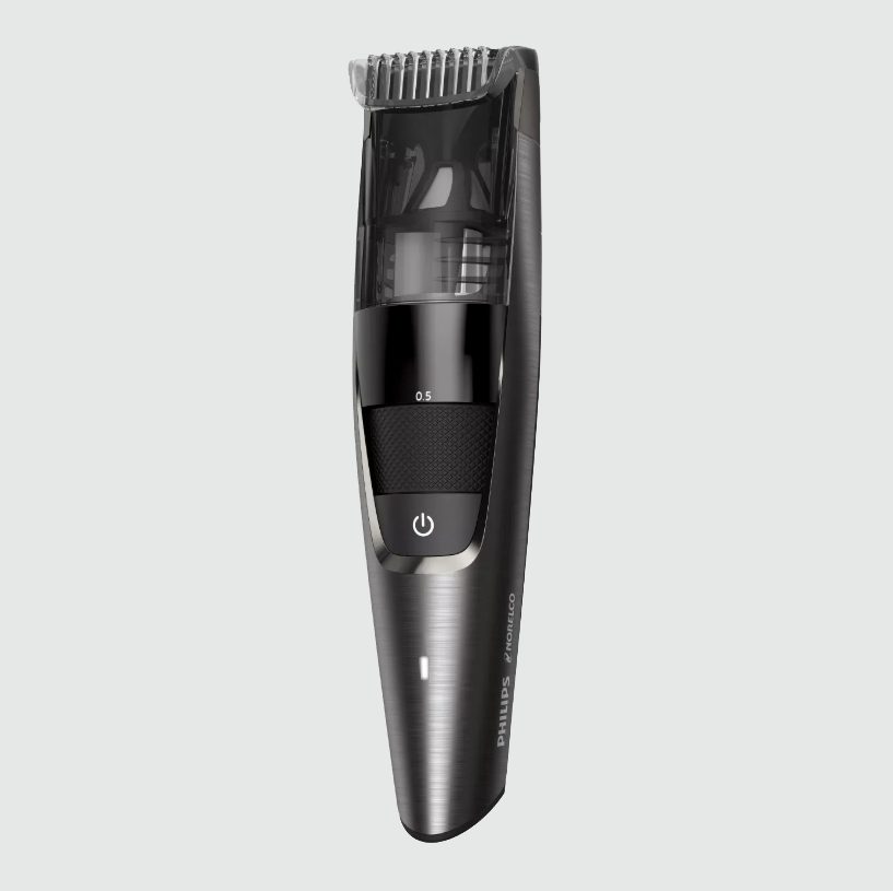 Electric beard trimmer standing; black and silver design, adjustable length dial. White background, "Philips Norelco" logo visible on handle.