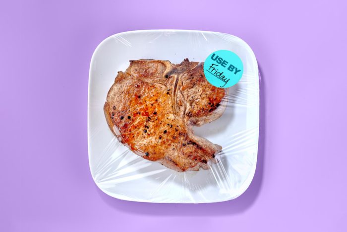Cooked Meat on a white plate with saran wrap on purple background. on the saran wrap is a sticker that says use by friday