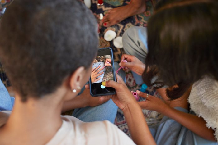 Woman photographing friend painting fingernails