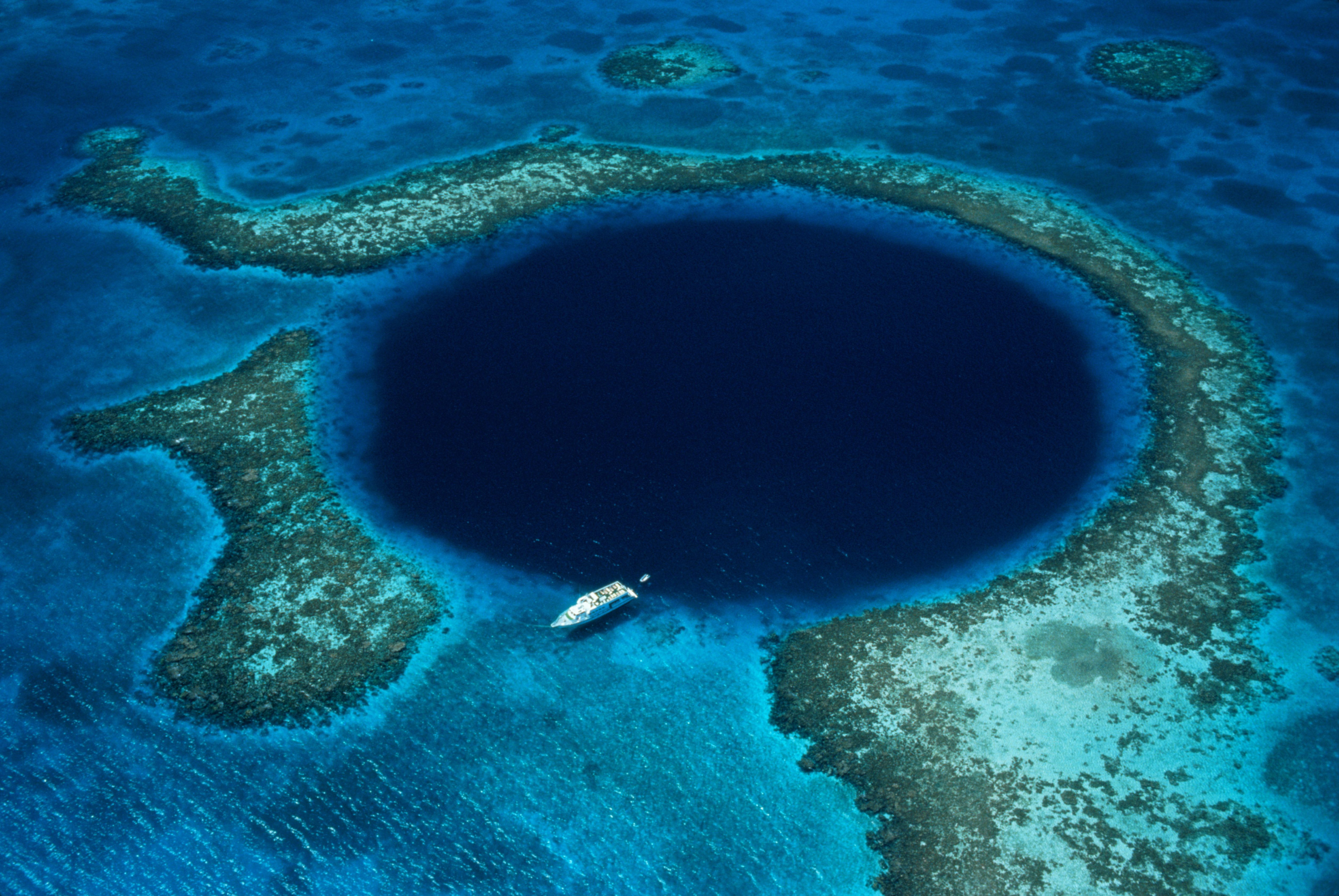 Belize, Lighthouse Reef, boat moored at Blue Hole, aerial view