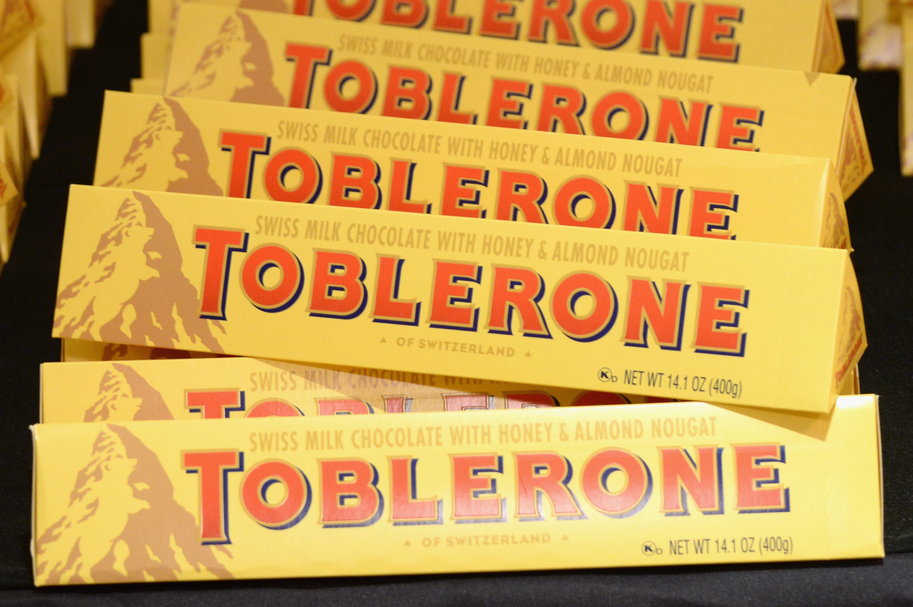 Packages of Toblerone chocolate stacked together, displaying brand name and product details, set in a store display.