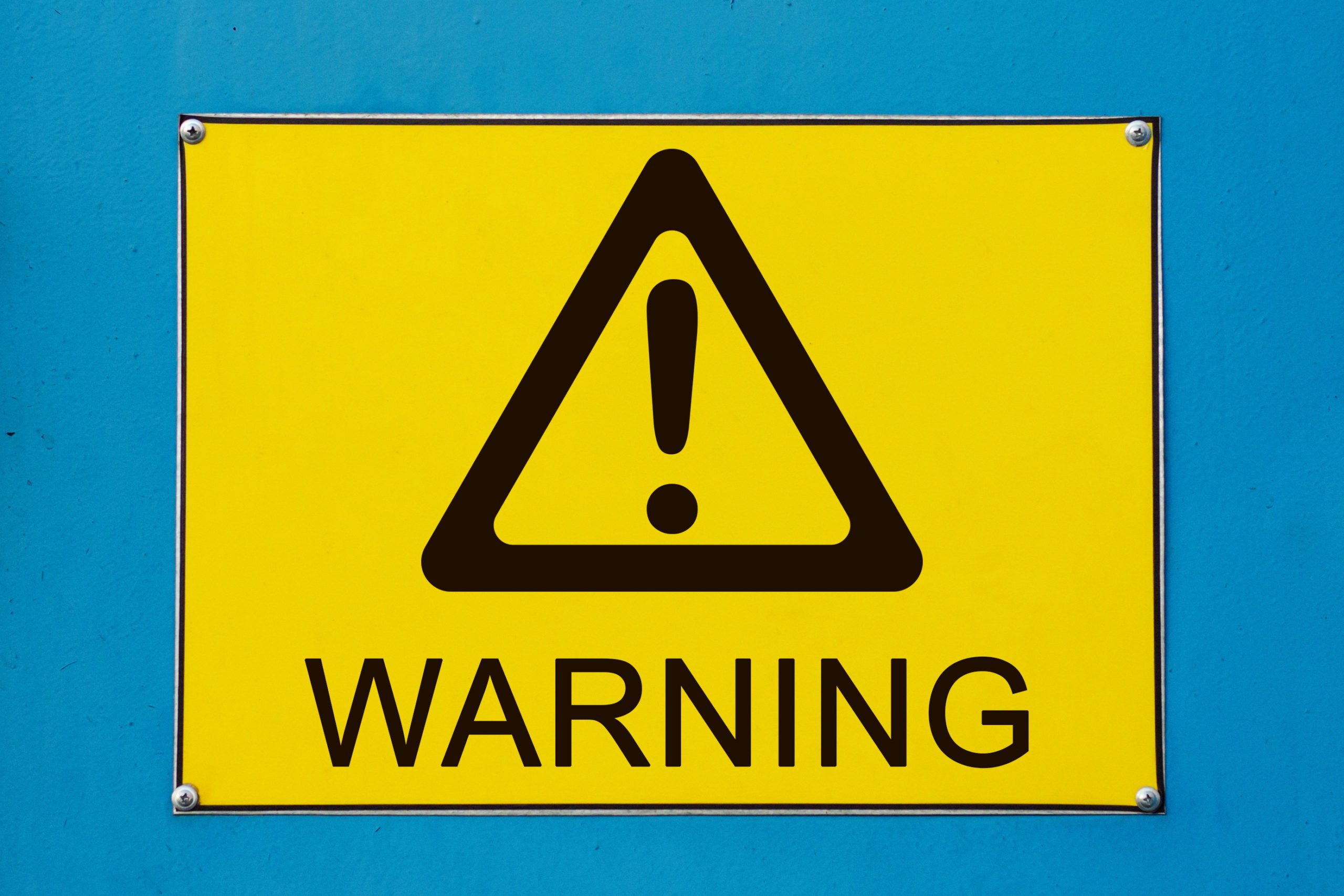 Warning sign on yellow metallic board